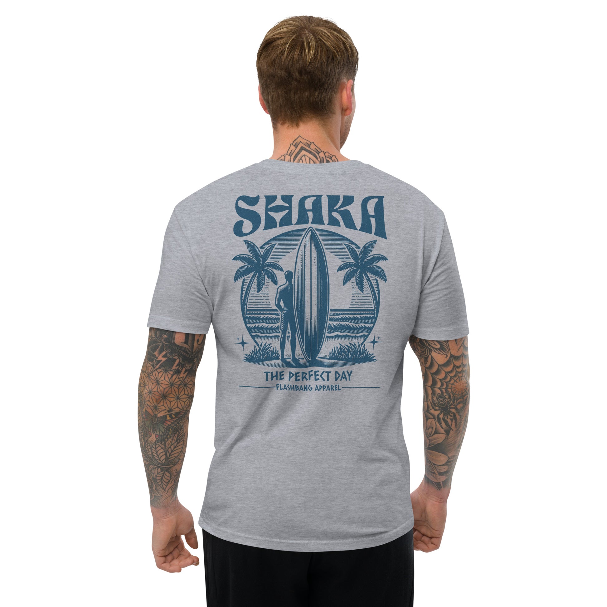 Man wearing a gray t-shirt with a 'Shaka' design on the back, featuring palm trees and a surfer.