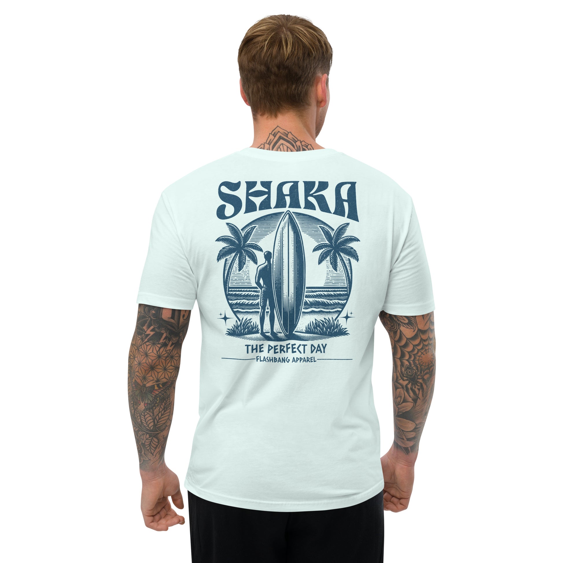 Man wearing a light blue t-shirt with 'Shaka' design on the back, featuring palm trees and a surfer.
