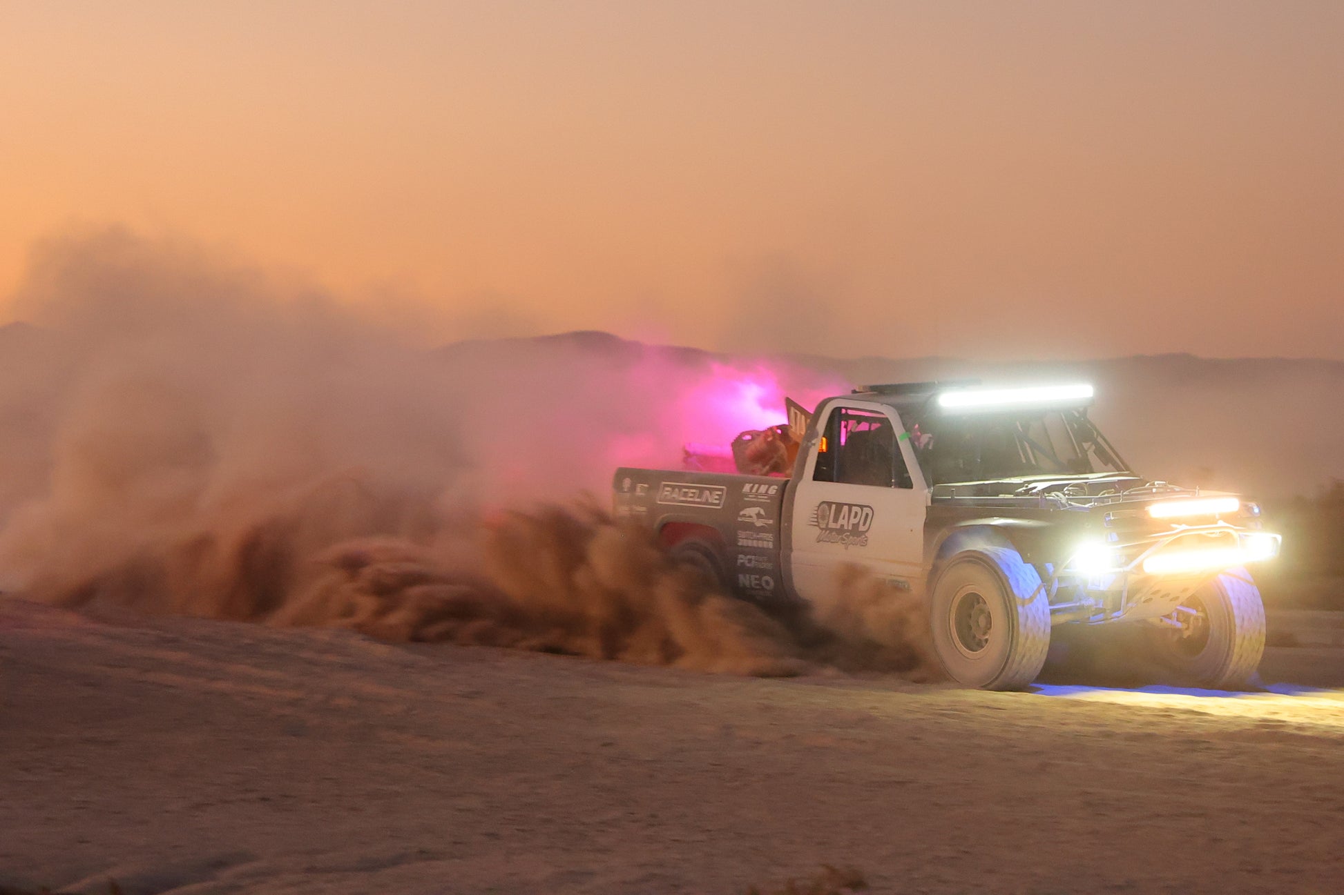 Dirt bike racing at night with bright lights on a dirt track