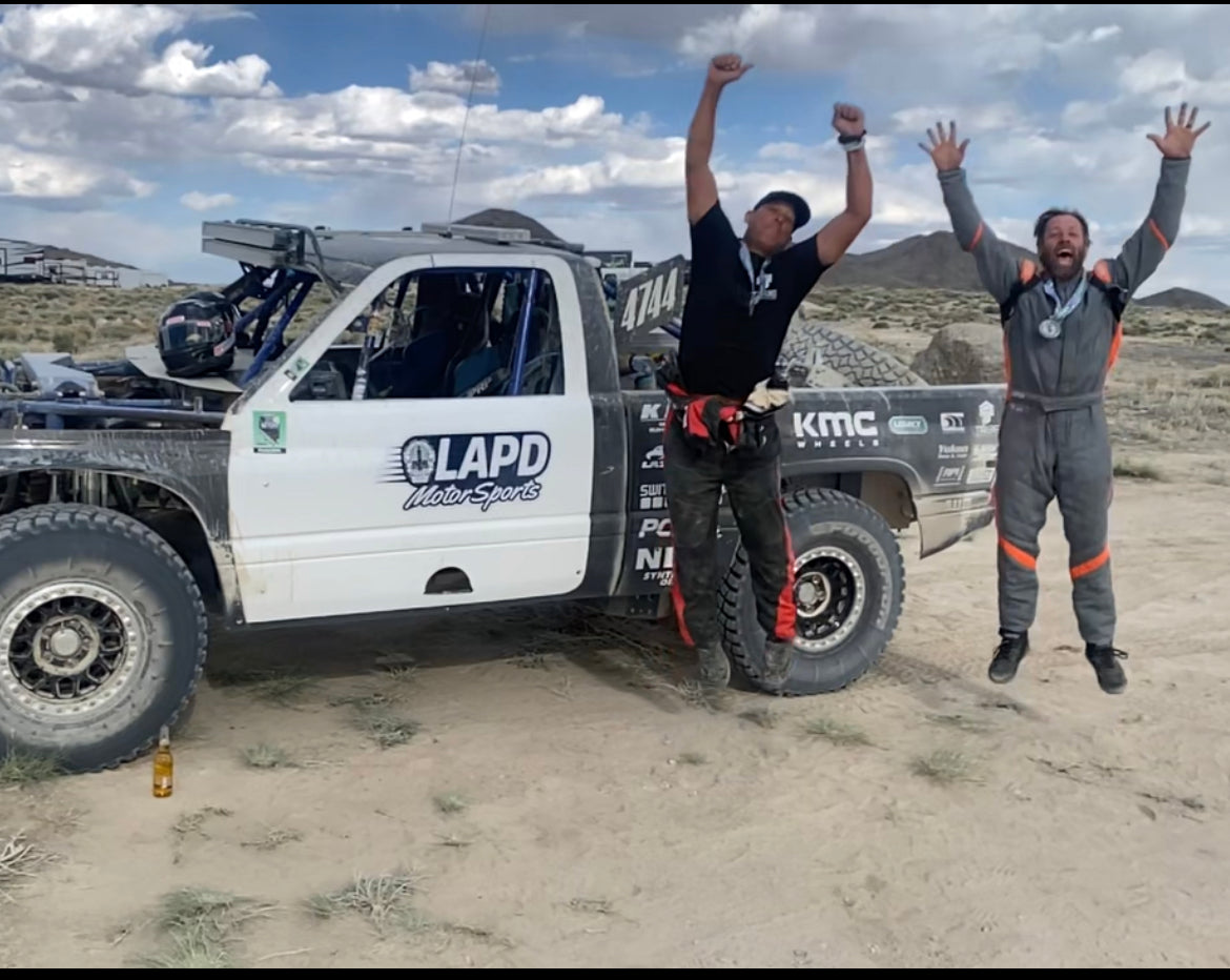 Two people celebrating in front of a truck with visible branding in an outdoor setting.