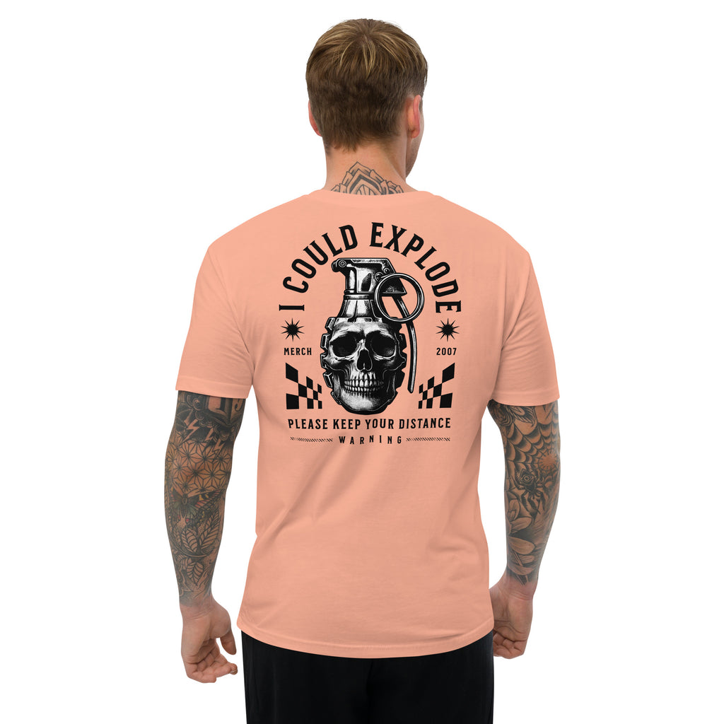 Man wearing a peach t-shirt with a graphic design on the back featuring a skull and grenade.