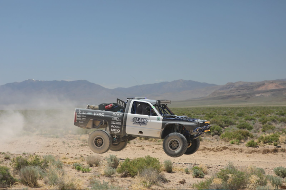 Off-road vehicle driving on a desert landscape with mountains in the background